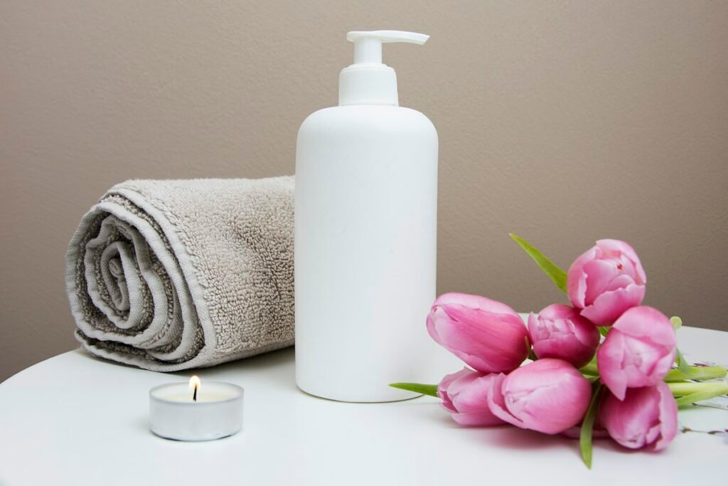 Spa towels, a pump bottle and pink flowers arranged for a relaxing massage setting